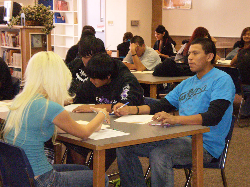 Several teens talking and working at a school table.