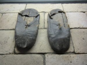Worn leather shoes resting on brick floor