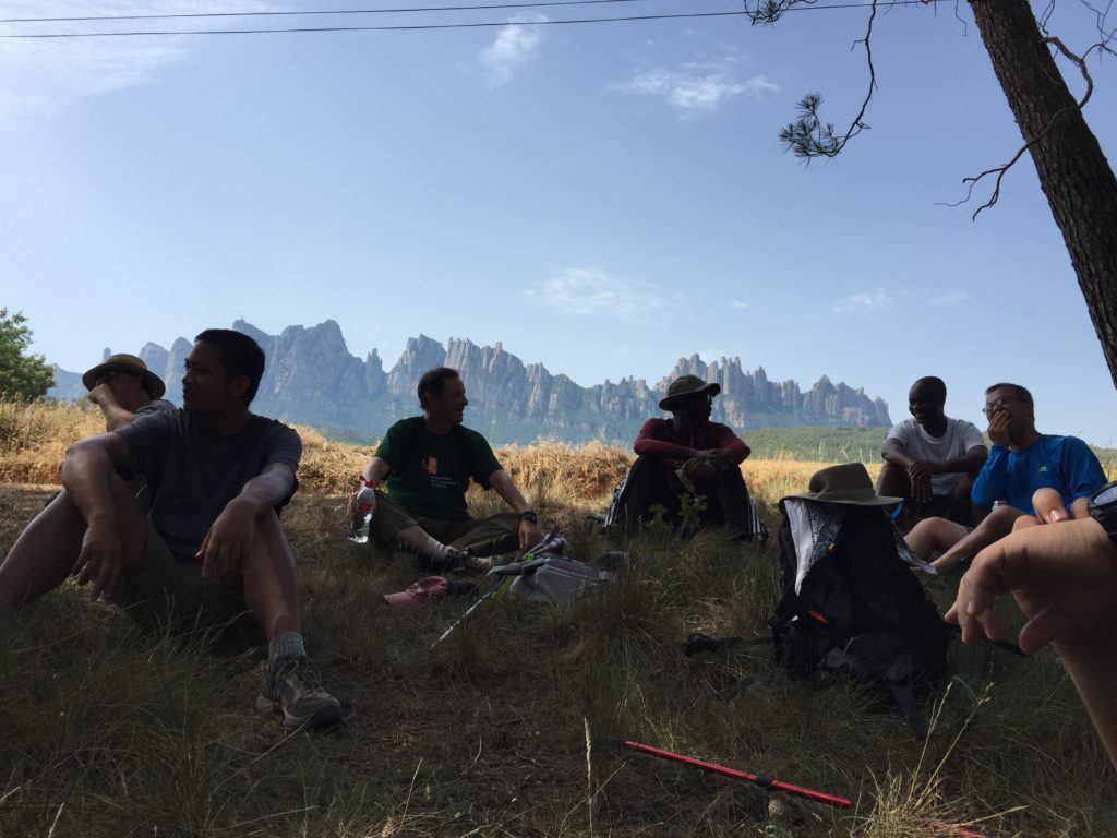 Pilgrims resting with jagged mountains in the backround.