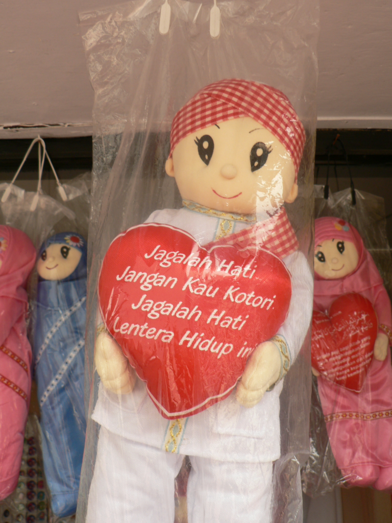 Cloth doll holding a heart with writing on it.